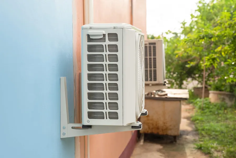Air conditioning condensing unit mounted on an exterior wall
