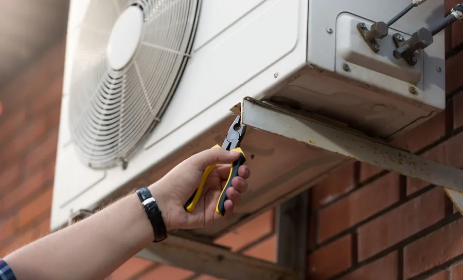 Technician installing an AC outdoor unit on a residential property