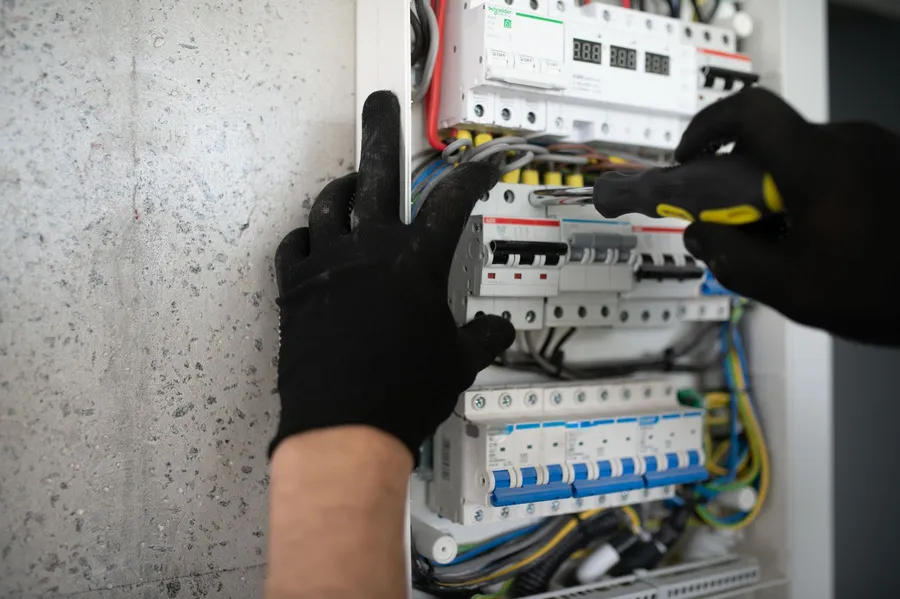 Electrician inspecting a switchboard panel in a French property