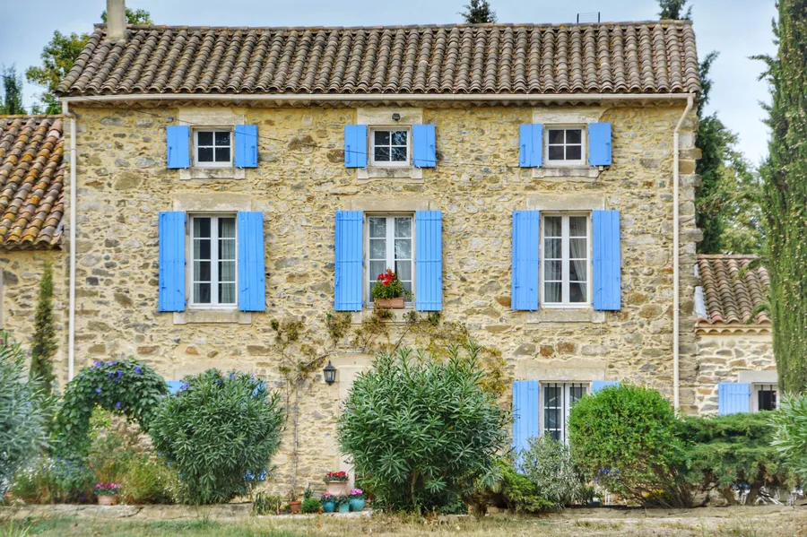 Stone house on the Cote d'Azur with canal-tile roof, single-glazed windows and painted wooden shutters