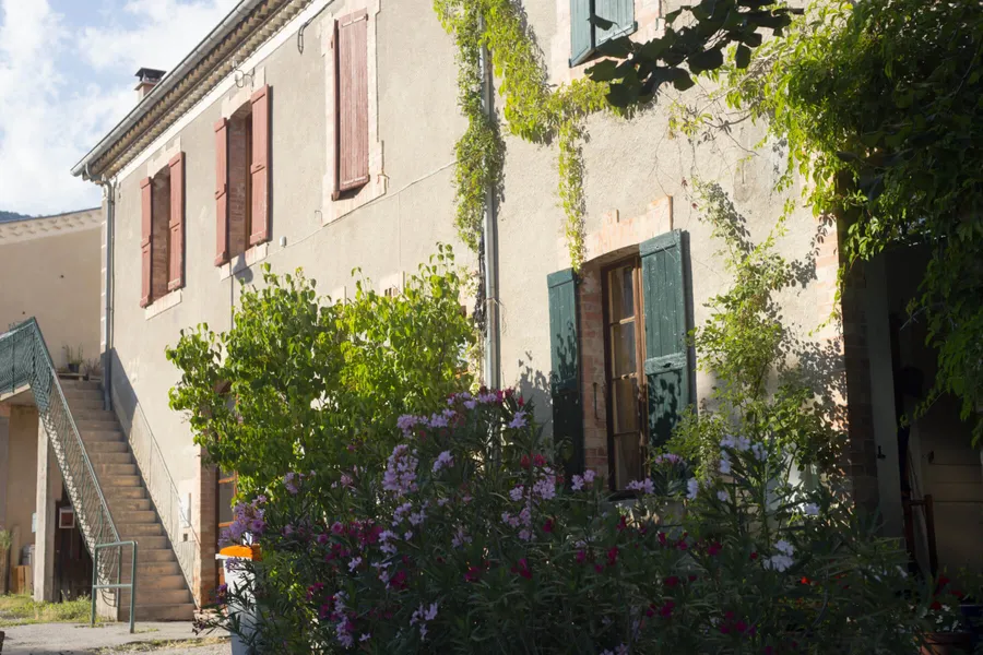 Shuttered stone village house with climbing plants and oleander in the south of France