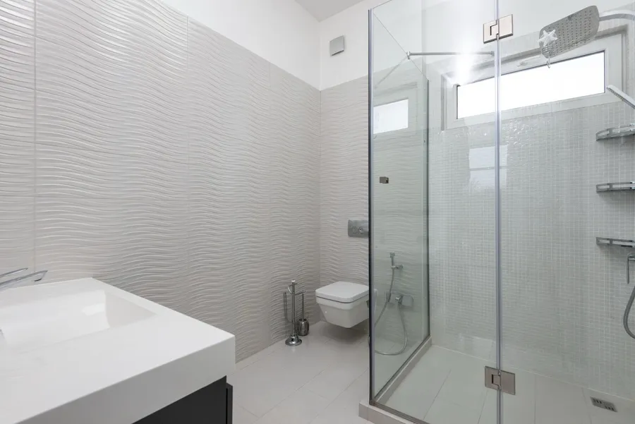 Small white shower room with a glass corner shower enclosure, a wall-hung WC and white wall tiles